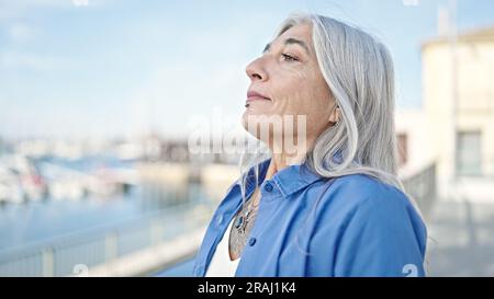 Donna dai capelli grigi di mezza età che respira al mare Foto Stock