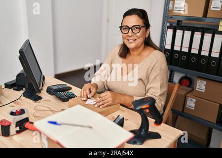 Medio età ispanica donna ecommerce business worker preparare il pacchetto in ufficio Foto Stock