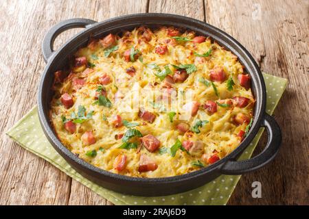 Croccante di patate grattugiate, porri, uova e pancetta affumicata a dadini da vicino in una padella sul tavolo. Orizzontale Foto Stock