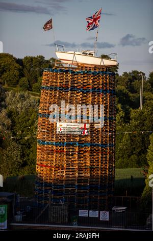 Un'imbarcazione battente bandiera Union Jack posta sulla cima della pira con uno striscione che recita "No Irish Sea Border" sul Moygashel Bonfire, Co Tyrone, prima che venga accesa sabato. Data immagine: Lunedì 3 luglio 2023. Foto Stock