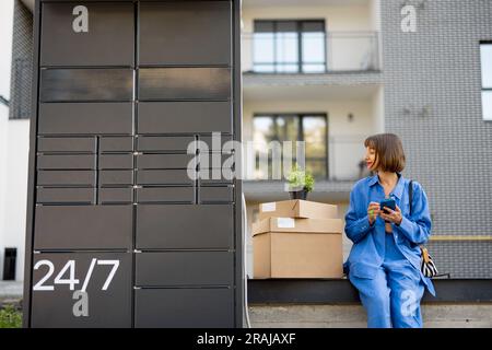 Donna con pacchi vicino alla macchina per ufficio postale all'aperto Foto Stock