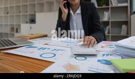 Primo piano delle mani di una donna d'affari utilizzando un calcolatore per controllare le finanze e i guadagni aziendali e il budget. Donna d'affari che calcola le spese mensili Foto Stock