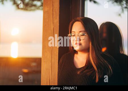 Ritratto all'aperto di un modello asiatico più taglie al tramonto, indossando occhiali da vista Foto Stock