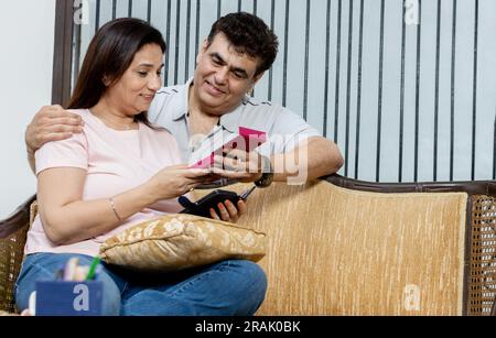 Marito indiano che copre gli occhi della moglie, fa una sorpresa di compleanno, le fa un regalo a casa. Coppia millenaria che celebra il b-day insieme, enjoyi Foto Stock