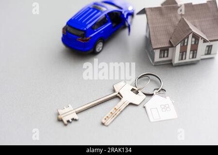 modello di auto e casa in vendita con denaro, chiave su sfondo, concetto di casa in vendita, primo piano. Foto Stock