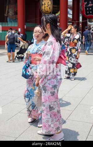 Tokyo, Giappone - 14 giugno 2023: Le donne che indossano i tradizionali kimono giapponesi camminano lungo le strade di Tokyo, di fronte al tempio Foto Stock
