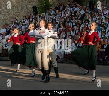 Dobele, Lettonia - 27 maggio 2023. Ballerini folcloristici sorridenti in movimento di fronte ai cantanti del coro popolare durante la XXVII canzone lettone nazionale e la XV Foto Stock