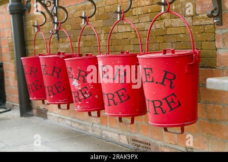 Linea di secchi antincendio galvanizzati di colore rosso che contengono sabbia sulla piattaforma della stazione Royal Wolferton in disuso, Wolferton, Inghilterra Regno Unito Foto Stock