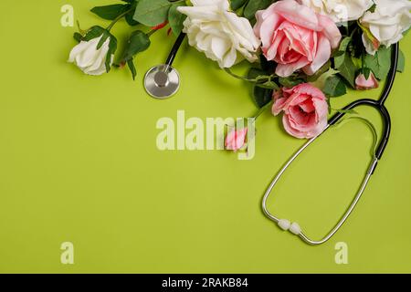 Fiori di rosa e stetoscopio su sfondo verde. Giorno del Dottore nazionale. Buon giorno dell'infermiera, biglietto d'auguri con spazio per le copie Foto Stock