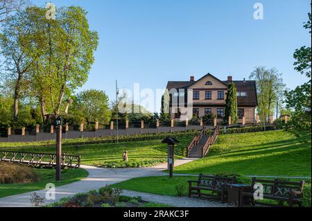 Parco della città vecchia di Kuldiga con sentieri per passeggiate ed edifici adiacenti, Lettonia Foto Stock