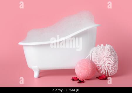Piccola vasca da bagno con schiuma, spugna e bombe da bagno su sfondo lilla  Foto stock - Alamy