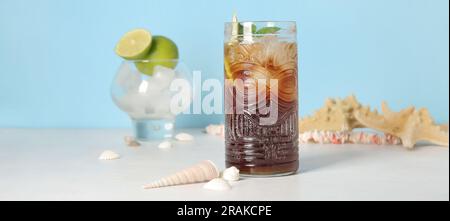 Bicchiere di cocktail Cuba Libre freddo, conchiglie di mare e stelle di pesca sul tavolo Foto Stock