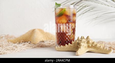 Bicchiere di freddo Cuba Libre cocktail e stelle di pesca su sfondo bianco Foto Stock