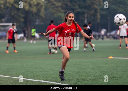 Una ragazza pratica le sue abilità calcistiche durante una serata su un campo comunitario del centro cittadino Foto Stock