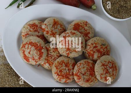 Bajra di carote. Torta di riso salata al vapore preparata da una pastella di lenticchie nere fermentate e miglio perlato non lucido con carr appena grattugiato Foto Stock