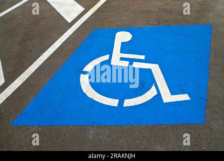 Un posto auto per i conducenti disabili contrassegnato con il simbolo internazionale di accesso (ISA) che mostra una persona su una sedia a rotelle. Foto Stock