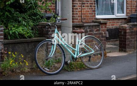 Una bicicletta incatenata e fissata saldamente a un lampione in una strada residenziale Foto Stock