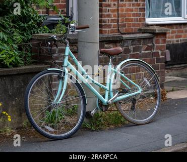 Una bicicletta incatenata e fissata saldamente a un lampione in una strada residenziale Foto Stock