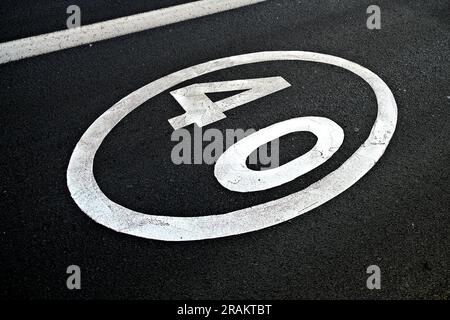 40, numero quaranta, segnale del limite di velocità verniciato in vernice riflettente bianca su pavimentazione in asfalto nero. Foto Stock