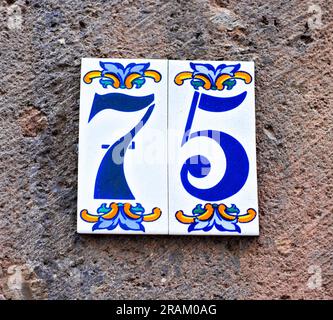 75, numero settantacinque, piastrelle decorative su superficie grigia Foto Stock