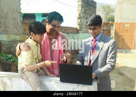 Felice famiglia indiana seduta con il banchiere o consulente finanziario che usa il computer portatile seduto fuori casa. Prestito per l'istruzione Foto Stock