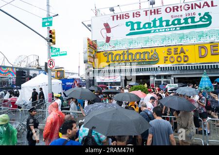 Brooklyn, NY, USA, 4 luglio 2023, la folla si raduna e cerca riparo dalle forti piogge a Brooklyn, NY, USA, mentre il concorso annuale di mangiatori di hot dog di Nathan a Coney Island è stato respinto a causa del maltempo il 4 luglio 2023 Foto Stock