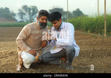 Un medico sta testando il terreno per migliorare i benefici agricoli. Esperto del suolo che fa capire all'agricoltore la qualità del suolo. Foto Stock