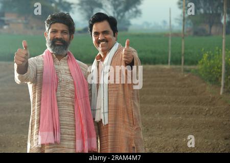 Splendida composizione di due agricoltori indiani in piedi nel campo con le mani piegate. Concetto agricolo che ritrae gli agricoltori al lavoro. Foto Stock