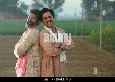Splendida composizione di due agricoltori indiani in piedi nel campo con le mani piegate. Concetto agricolo che ritrae gli agricoltori al lavoro. Foto Stock