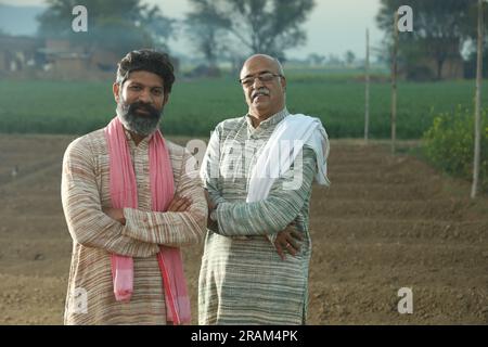 Splendida composizione di due agricoltori indiani in piedi nel campo con le mani piegate. Concetto agricolo che ritrae gli agricoltori al lavoro. Foto Stock