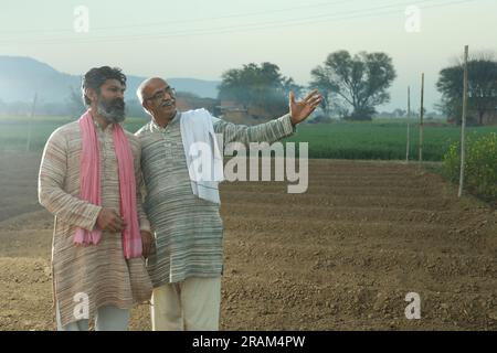 Splendida composizione di due agricoltori indiani in piedi nel campo con le mani piegate. Concetto agricolo che ritrae gli agricoltori al lavoro. Foto Stock