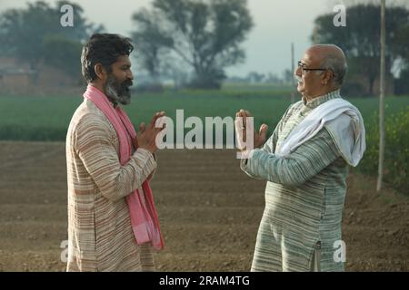 Splendida composizione di due agricoltori indiani in piedi nel campo con le mani piegate. Concetto agricolo che ritrae gli agricoltori al lavoro. Foto Stock