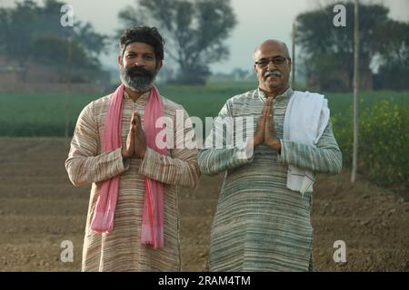 Splendida composizione di due agricoltori indiani in piedi nel campo con le mani piegate. Concetto agricolo che ritrae gli agricoltori al lavoro. Foto Stock