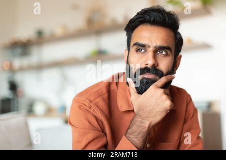 Ritratto del pensivo giovane uomo arabo che pensa in salotto Foto Stock