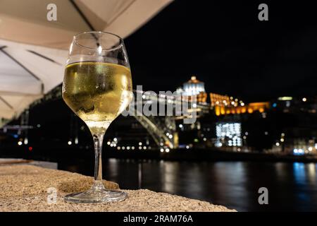 Bevendo vino bianco Porto in un ristorante a Porto vicino al fiume la sera con una bella vista. Foto Stock