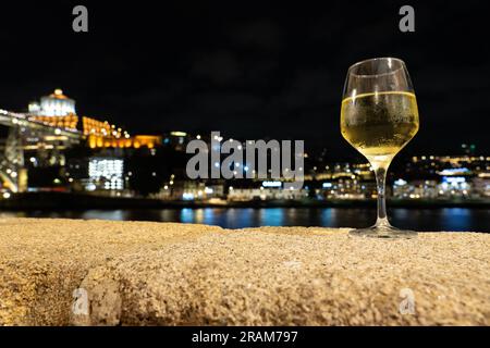 Bevendo vino bianco Porto in un ristorante a Porto vicino al fiume la sera con una bella vista. Foto Stock