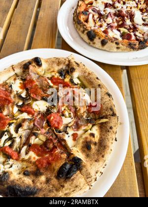 Pizza napoletana italiana servita su piatti, cotta nel forno a legna. Foto Stock
