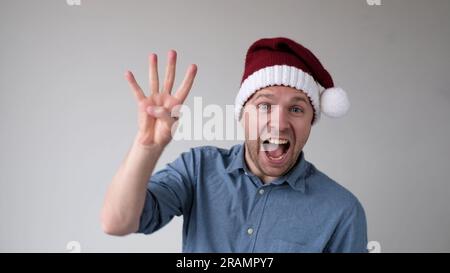 Funny Man in a New Year's Hat Counts Fingers, come mostra i numeri Foto Stock