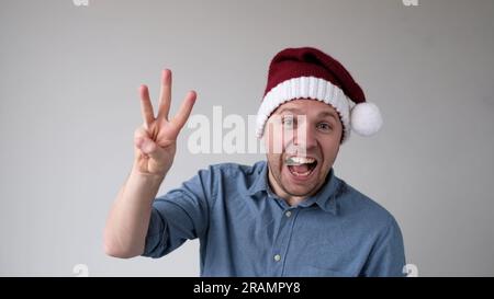 Funny Man in a New Year's Hat Counts Fingers, come mostra i numeri Foto Stock