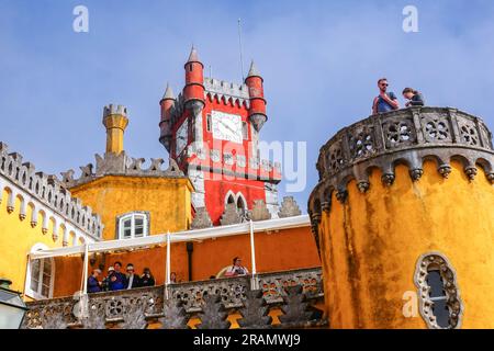 Facciata colorata con i quartieri reali e la torre dell'orologio rosso presso il Palácio da pena o lo storico castello del palazzo Palácio da pena a Sintra, Portogallo. Il castello da favola è considerato uno dei migliori esempi di architettura romanticistica portoghese del XIX secolo al mondo. Foto Stock