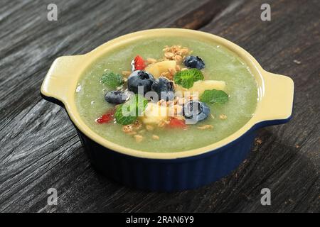 Kiwi Slush Smoothie drink Bowl con salsa di mirtilli, ananas, granola e fragole. Frutta fresca estiva Concept succhi salutari Fruity Bowl Foto Stock