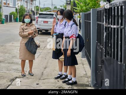 Un'insegnante tailandese e le sue figlie tutte vestite con le loro uniformi scolastiche. Foto Stock