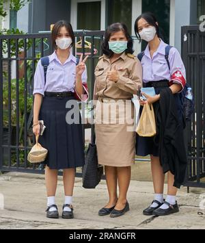 Un'insegnante tailandese e le sue figlie tutte vestite con le loro uniformi scolastiche. Foto Stock