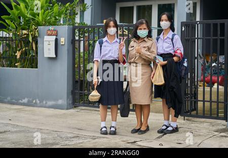 Un'insegnante tailandese e le sue figlie tutte vestite con le loro uniformi scolastiche. Foto Stock