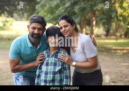 Famiglia indiana felice di padre, madre, figlio e una figlia che si divertono nel parco verde in un giorno in un ambiente fresco e verde. Foto Stock