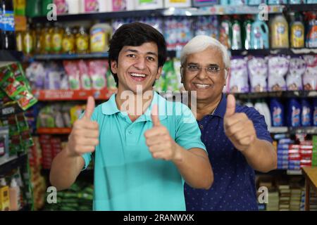 Nonno e figlio acquistano in un negozio di alimentari. Comprare della spesa al supermercato. Padre e figlio allegri che tengono il prodotto in mano nel centro commerciale. Foto Stock