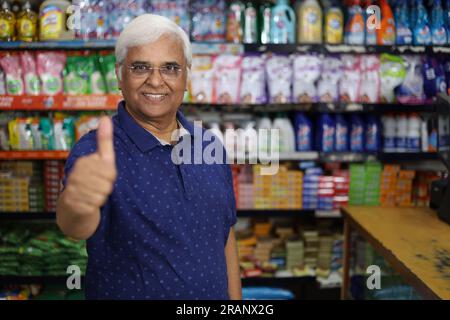 Ritratto di un anziano indiano felice e sorridente che acquista in un negozio di alimentari. Nonno sicuro e in forma che acquista generi alimentari per casa in un supermercato. Foto Stock