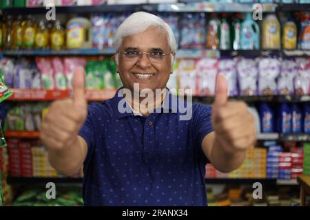 Ritratto di un anziano indiano felice e sorridente che acquista in un negozio di alimentari. Nonno sicuro e in forma che acquista generi alimentari per casa in un supermercato. Foto Stock