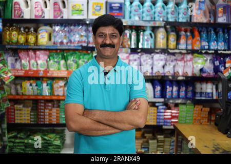 Ritratto di un uomo indiano felice e sorridente che acquista in un negozio di alimentari. Comprare della spesa per casa in un supermercato. Uomo sicuro e in forma nei baffi. Foto Stock