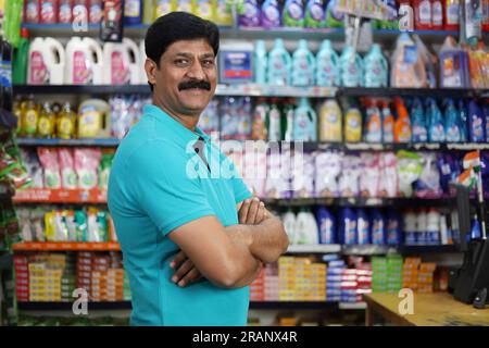 Ritratto di un uomo indiano felice e sorridente che acquista in un negozio di alimentari. Comprare della spesa per casa in un supermercato. Uomo sicuro e in forma nei baffi. Foto Stock